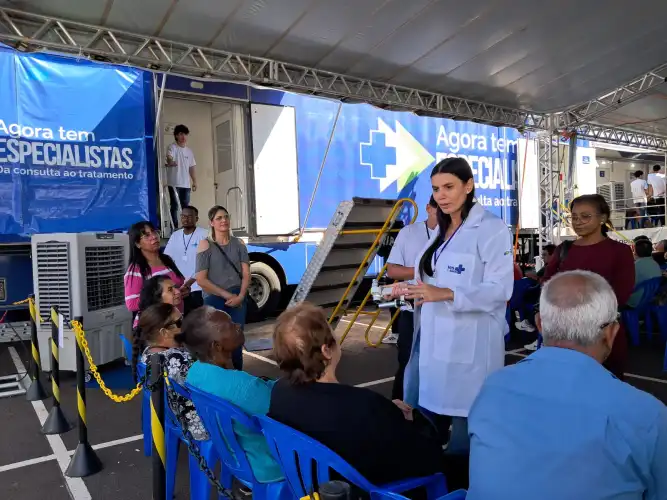 Estrutura móvel montada no Londrina Norte Shopping agiliza a fila de espera do SUS. Para que o ritmo de atendimentos continue, Secretaria de Saúde faz apelo para que pacientes atualizem seus telefones nas UBSs. Em apenas duas semanas de funcionamento no estacionamento do Londrina Norte Shopping, as unidades móveis do programa Agora tem Especialistas já transformaram a realidade de centenas de londrinenses. Mais de 600 cirurgias de catarata foram realizadas, e o local segue recebendo diariamente pacientes para os acompanhamentos de pós-operatório, que começam logo no dia seguinte à intervenção. A estrutura ágil e o atendimento em série têm sido a solução para encurtar uma fila de espera que, para muitos, significava a perda gradual da independência e da qualidade de vida. A alegria de voltar a enxergar A recuperação da visão tem trazido alívio imediato para os pacientes. Terezinha Vicente da Costa aguardava na fila desde a sua primeira consulta, há quase um ano. “Eu nunca tinha feito cirurgia. Já não estava enxergando nada, só uma fumaça tampando tudo. Me dava uma tristeza, porque se minhas amigas não parassem para falar comigo eu nem sabia quem era. Agora, assim que operei já estou enxergando bem. Está mil maravilhas”, comemorou Terezinha. Aos 75 anos, dona Maria das Dores da Silva também compareceu à carreta para o primeiro retorno após operar o olho direito. Amparada pela filha Alessandra, ela elogiou o acolhimento da equipe, que não a deixou sentir dor, e já faz planos para o fim do resguardo: "Gosto muito de cozinhar. Assim que tiver alta, vou fazer muito salgado". O sentimento é compartilhado pela costureira Irene Lopes Pinheiro, que retornou para avaliar o olho direito e já está com a cirurgia do esquerdo agendada na unidade móvel. "Quando passar a recuperação, o dia a dia vai voltar ao normal, quero principalmente voltar a costurar", projetou. O trabalho nos bastidores Para que a linha de cuidados funcione de forma ágil, uma equipe de mais de 40 profissionais atua nas unidades móveis. O protocolo exige que, nos 30 dias após a cirurgia, cada paciente passe por quatro consultas de retorno. Todo esse acompanhamento é garantido pela equipe da carreta, mesmo quando a estrutura for deslocada para outro município. Para os profissionais, o ritmo intenso é compensado pelos resultados. A médica oftalmologista Malu Inês Perez Moura, natural de Londrina, celebra a chance de atuar em sua cidade após seis anos viajando o Brasil com o programa. "É corrido, mas muito gratificante saber que as pessoas vão melhorar a visão. A maior parte do nosso público tem mais de 60 anos, e eles estão amando voltar a enxergar", relatou. Atenção à fila de espera: atualize seu cadastro! Apesar do sucesso das cirurgias, a Secretaria Municipal de Saúde enfrenta um obstáculo comum: a dificuldade em localizar os pacientes na fila devido a telefones desatualizados. A assessora da pasta, Kátia Silva, reforça que o trabalho de agendamento segue intenso e pede a colaboração da população. Se você ou algum familiar aguarda por consultas ou cirurgias oftalmológicas, siga as orientações abaixo: Atualize seus dados: Vá até a Unidade Básica de Saúde (UBS) mais próxima da sua residência e confirme se o seu número de telefone (e de recados) está correto. Fique de olho no WhatsApp: A Secretaria de Saúde também utiliza o aplicativo de mensagens para fazer as convocações. Atenda as ligações: Nos próximos dias, não deixe de atender ligações, mesmo de números desconhecidos, pois pode ser a equipe de agendamento da cirurgia. "O atendimento na carreta é em série, então é muito ágil e resolutivo", conclui Kátia Silva, lembrando que a resposta rápida do paciente garante que a fila ande para todos.